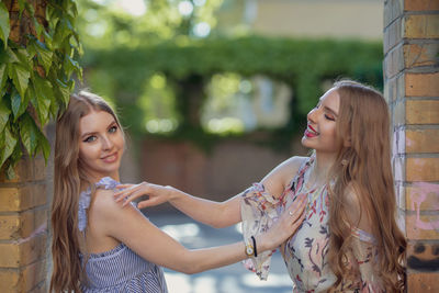 Smiling beautiful friends standing at doorway in park