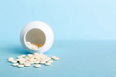 Pills spilling from bottle against blue background