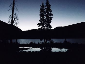 Silhouette trees by lake against sky during sunset