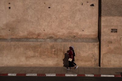 Rear view of man sitting on wall