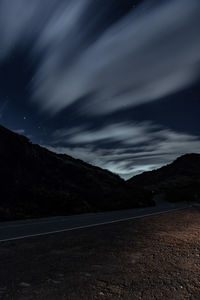 Road by mountains against sky at night
