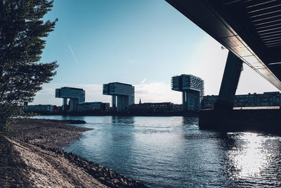 Buildings by river against sky in city