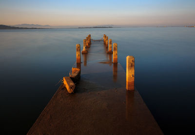 Pier over sea against sky during sunset