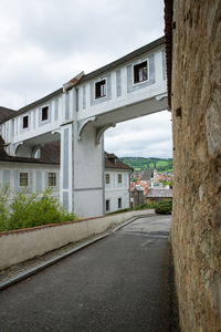 Empty road amidst buildings against sky in city