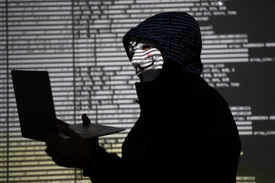 Hooded identity theft wearing an anonymous guy fawkes mask