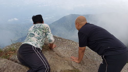 Rear view of people on mountain against sky