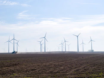 Windmills on field against sky