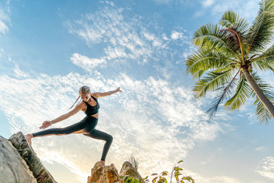 Woman stretching against sky