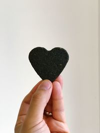 Close-up of hand holding heart shape over white background
