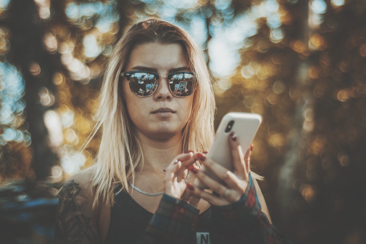 PORTRAIT OF YOUNG WOMAN USING SMART PHONE