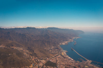 High angle view of sea and mountains against clear blue sky