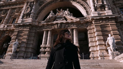 Woman standing by historic building