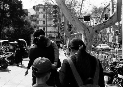 Rear view of people on street amidst buildings in city