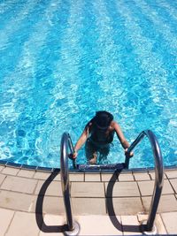 High angle view of woman on ladder in swimming pool