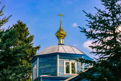 Beautiful christian church with golden domes among green trees.