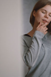 Portrait of beautiful young woman standing against wall