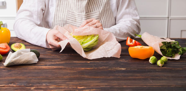 Midsection of woman eating food in kitchen at home