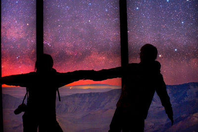 Silhouette couple standing against sky at night