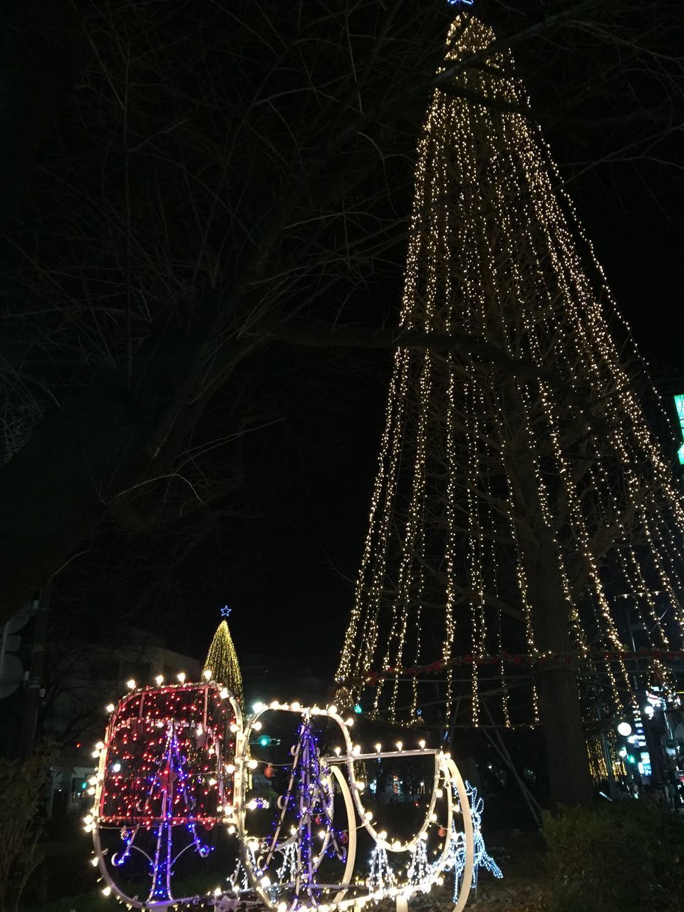 night, illuminated, christmas, celebration, christmas tree, christmas lights, city, architecture, christmas decoration, lighting equipment, low angle view, built structure, tree, building exterior, sky, no people, tree topper, christmas ornament, outdoors, skyscraper, christmas market, midnight