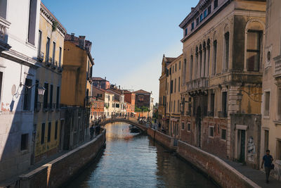 Bridge over canal amidst buildings against sky in city