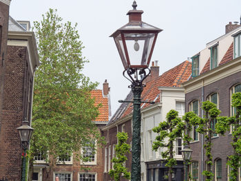 Low angle view of street light by building against sky