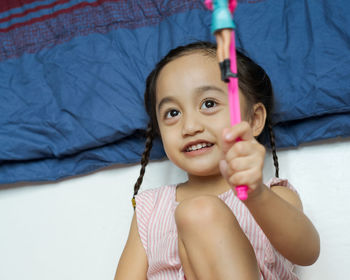 Smiling girl holding doll against curtain