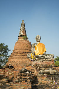 Low angle view of buddha statue by temple at ayutthaya historical park