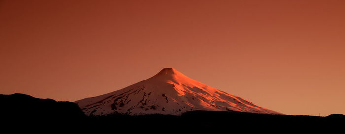 Scenic view of volcanic mountain against sky during sunset