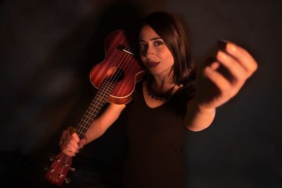 High angle of woman holding guitar against black background