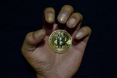 High angle view of human hand holding paper over black background