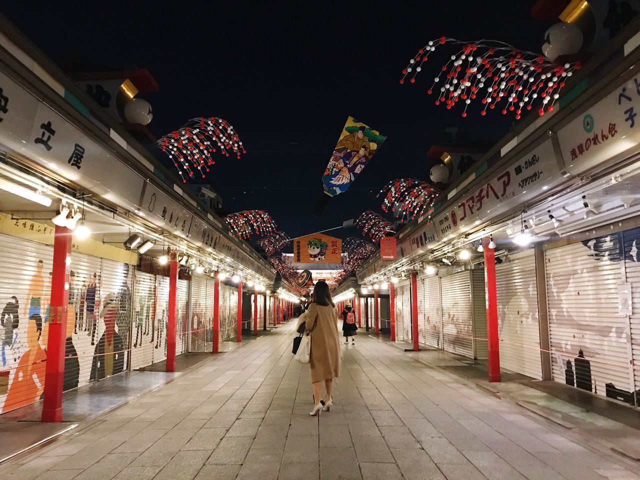 WOMAN WALKING ON ILLUMINATED STREET LIGHTS