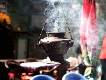 Close-up of smoke emitting from old rustic container hanging outdoors