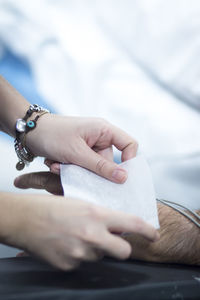 Cropped hands of female doctor putting bandage on hand