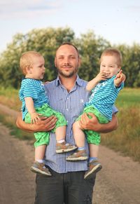 Portrait of smiling man carrying sons