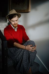 Portrait of young man sitting against wall