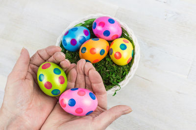 Cropped hands holding colorful easter eggs on table