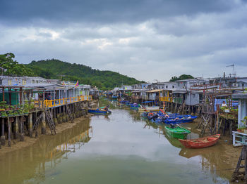 Fishing boats moored in river by city against sky