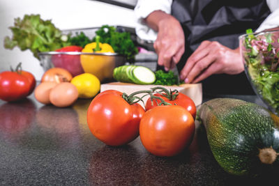 Midsection of woman chopping vegetables on kitchen counter at home