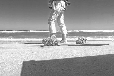 Low section of man standing on beach against sky