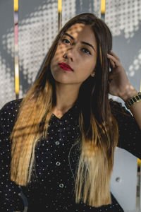 Portrait of young woman standing against wall