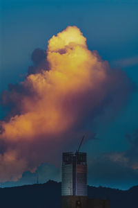 Low angle view of silhouette factory against sky during sunset