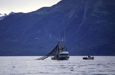 Sailboat sailing on sea against mountains