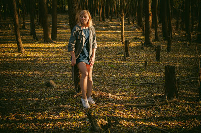 Full length portrait of young woman standing in forest