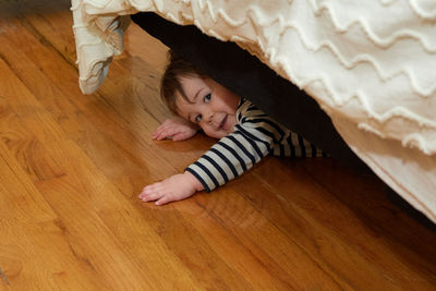 Cute boy toddler hiding under the bed