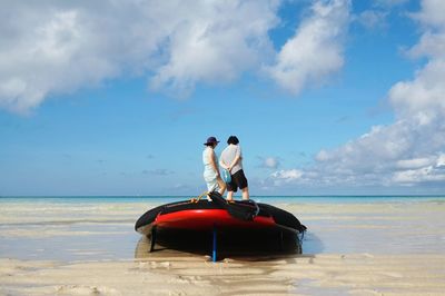 Couple standing on boat at shore against sky