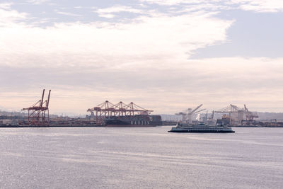 Cranes at commercial dock against sky