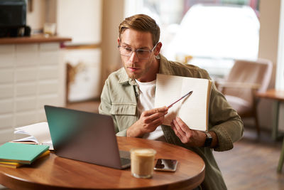 Young man using laptop while sitting on table