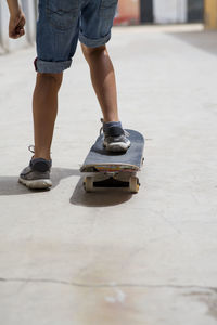 Low section of man skateboarding on road