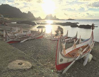 Boats moored on beach against sky during sunset