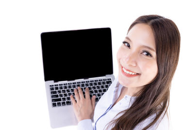 Portrait of smiling young woman using phone against white background